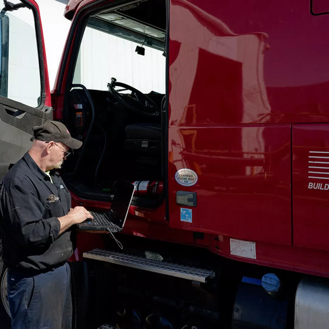 driver standing outside of a truck with a laptop