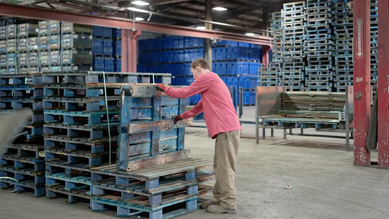 Warehouse worker organizing pallets inside logistics distribution center
