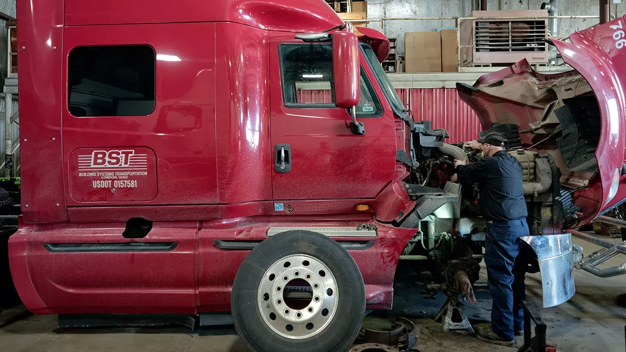 Truck mechanic servicing BST semi-truck engine inside maintenance garage Image