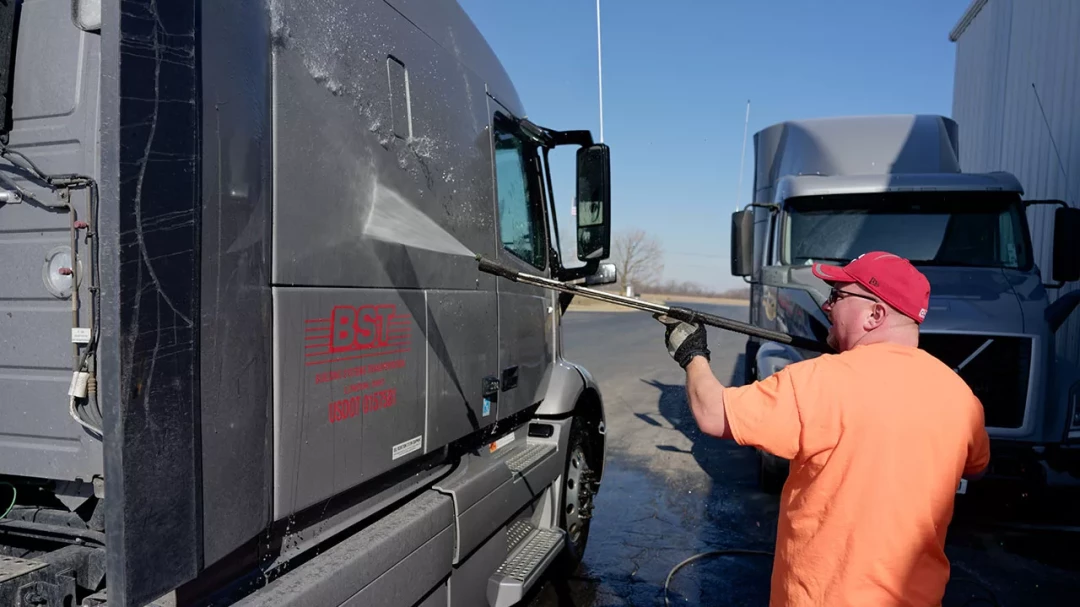 BST driver performing inspection beside parked semi-truck