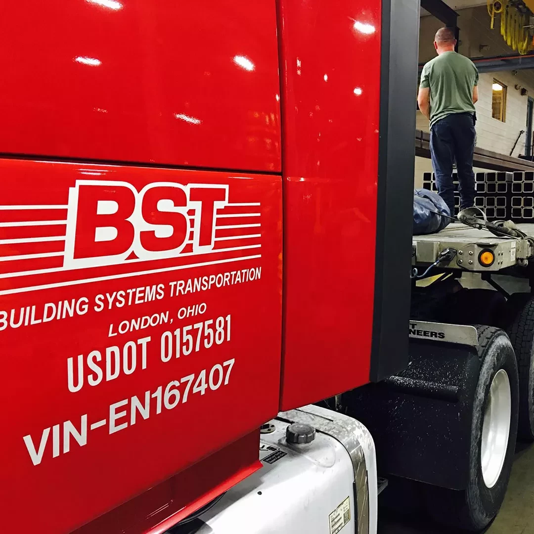 BST Building Systems Transportation semi-truck with driver inspecting trailer connection